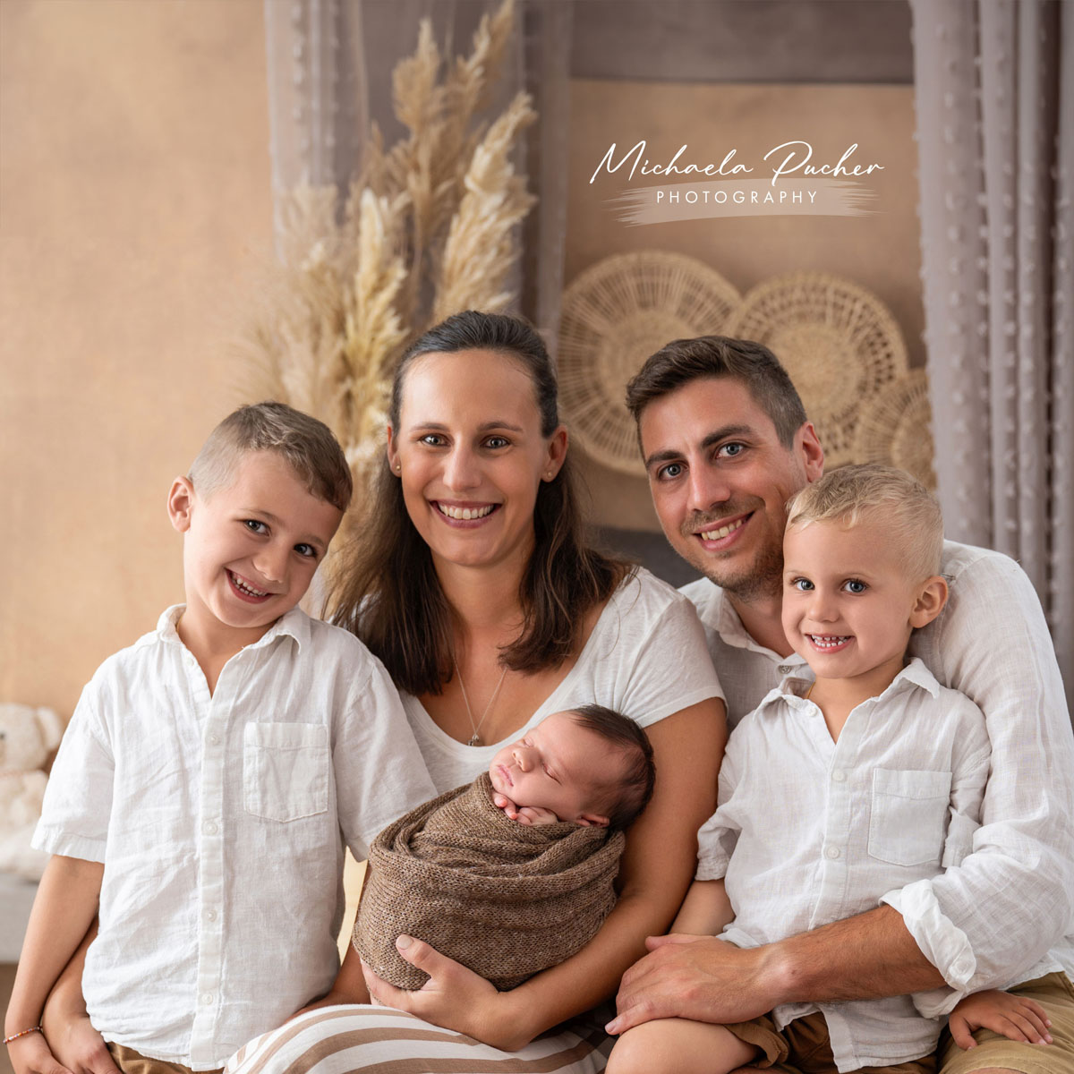 Familie mit zwei Kleinkindern und Neugeborenem im Studio, natürliche Familienfotografie in warmen Naturtönen